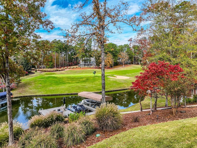 view of community featuring a water view, a yard, and a boat dock