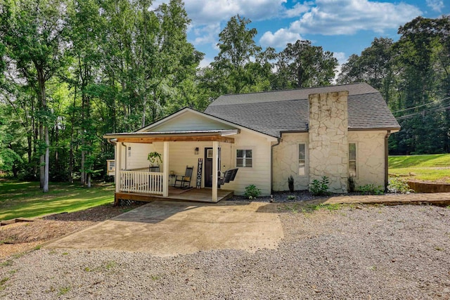 222 River Bend Dr, Eatonton, GA 31024 - view of front facade with stone siding, a porch, roof with shingles, and view of scattered trees