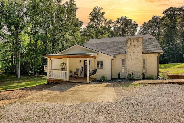 222 River Bend Dr, Eatonton, GA 31024 - view of front of home featuring stone siding, a porch, roof with shingles, and view of wooded area