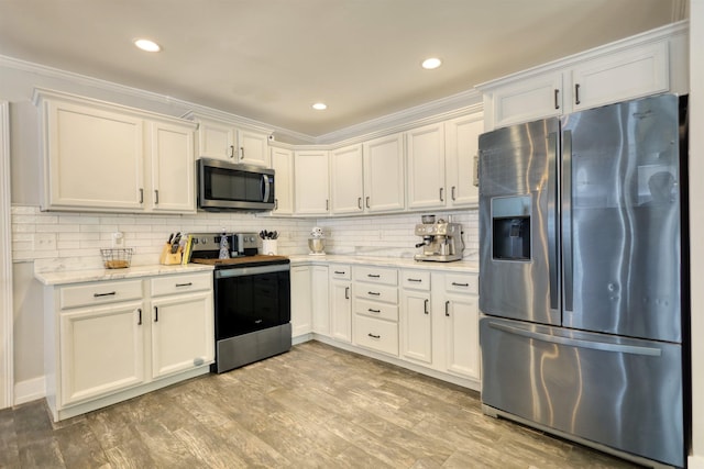 222 River Bend Dr, Eatonton, GA 31024 - kitchen featuring stainless steel appliances, decorative backsplash, white cabinets, light wood-style flooring, and ornamental molding