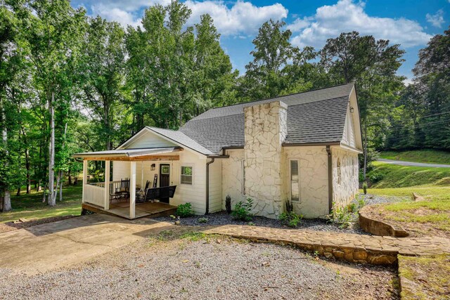 222 River Bend Dr, Eatonton, GA 31024 - view of front of home featuring a shingled roof, stone siding, a deck, and view of wooded area