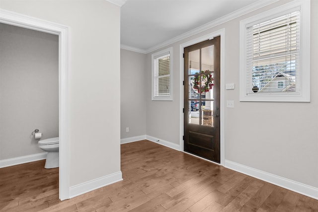 entryway with crown molding, healthy amount of natural light, baseboards, and wood finished floors