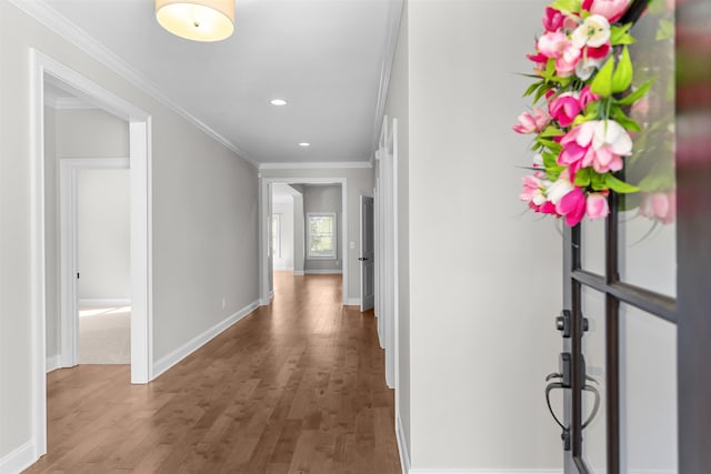 corridor with wood finished floors, baseboards, recessed lighting, and ornamental molding