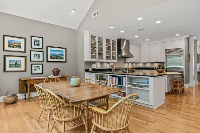 dining area featuring light wood finished floors, vaulted ceiling, recessed lighting, and baseboards