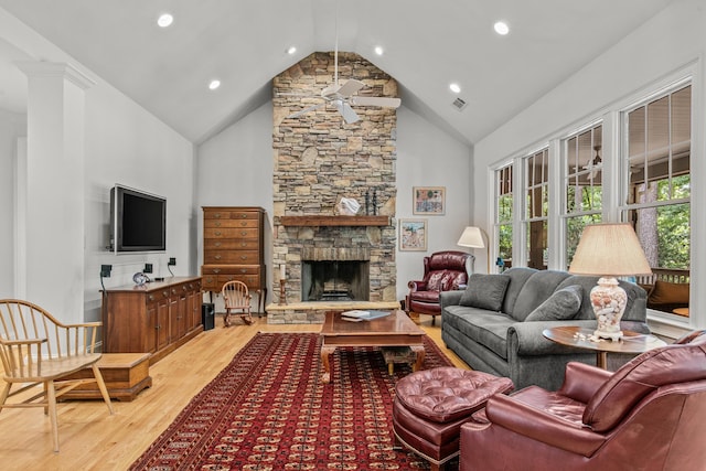 living room featuring light wood finished floors, a stone fireplace, high vaulted ceiling, and recessed lighting