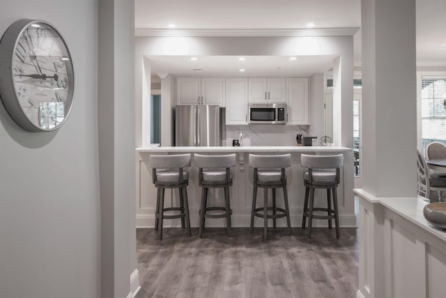 kitchen featuring appliances with stainless steel finishes, dark hardwood / wood-style flooring, a breakfast bar, and white cabinets