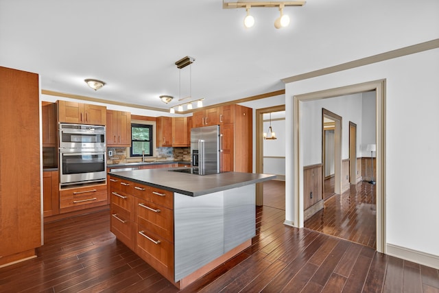 128 Turtle Ct, Eatonton, GA 31024 - kitchen with stainless steel appliances, dark countertops, dark wood finished floors, brown cabinets, and decorative light fixtures