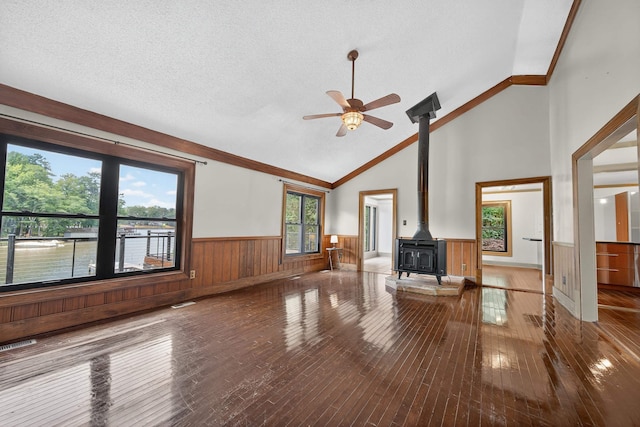 128 Turtle Ct, Eatonton, GA 31024 - unfurnished living room with a wood stove, a wainscoted wall, ceiling fan, hardwood / wood-style floors, and a textured ceiling
