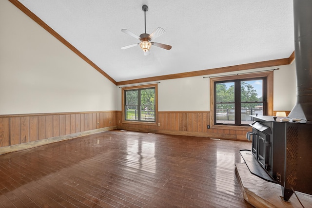 128 Turtle Ct, Eatonton, GA 31024 - unfurnished living room featuring a wood stove, a wainscoted wall, lofted ceiling, crown molding, and hardwood / wood-style floors