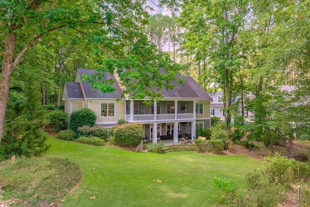 back of property featuring a yard, a sunroom, and a patio