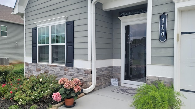  - property entrance with stone siding, a porch, and central AC