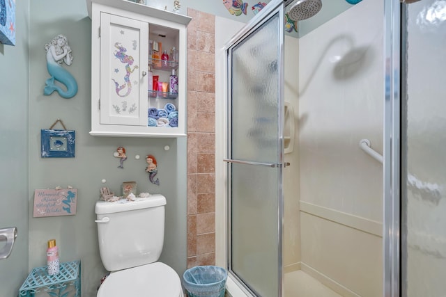 bathroom featuring a shower with shower door and toilet