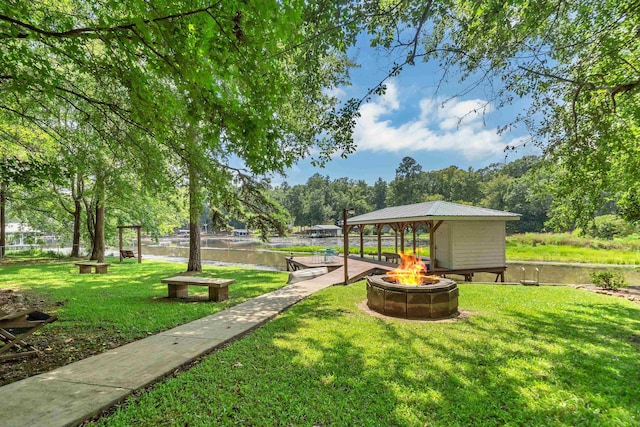 view of yard featuring a gazebo, a water view, and an outdoor fire pit