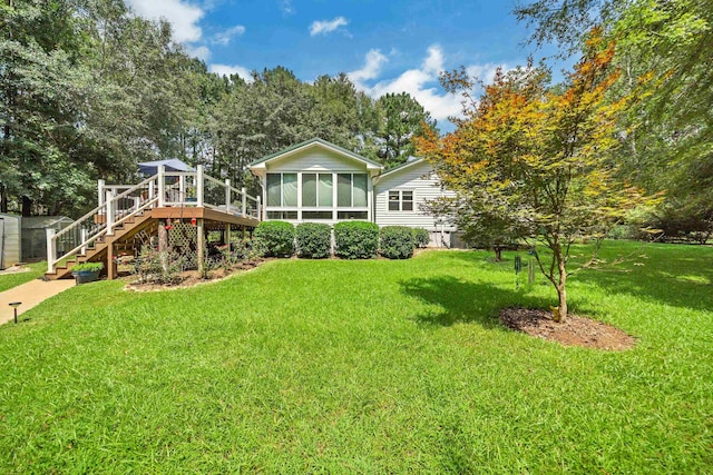 rear view of house featuring a wooden deck, a sunroom, and a yard