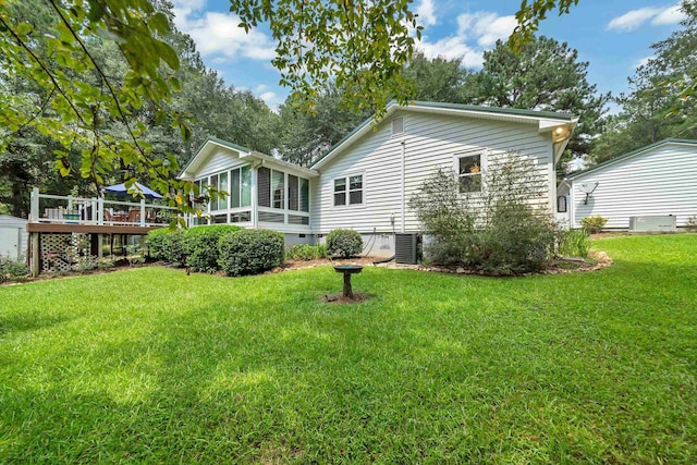 back of property featuring a wooden deck, a sunroom, and a lawn