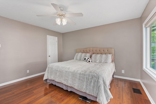bedroom with baseboards, wood finished floors, and multiple windows