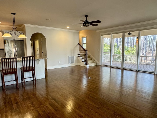 unfurnished living room featuring dark wood-style floors, visible vents, baseboards, ceiling fan, and crown molding