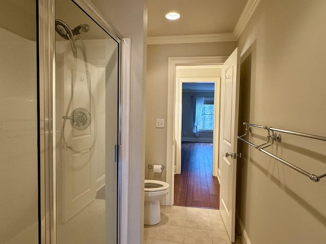 bathroom featuring tile patterned flooring, baseboards, toilet, ornamental molding, and a stall shower