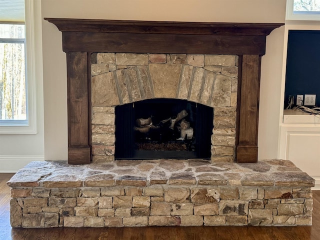 room details featuring a stone fireplace, wood finished floors, and baseboards