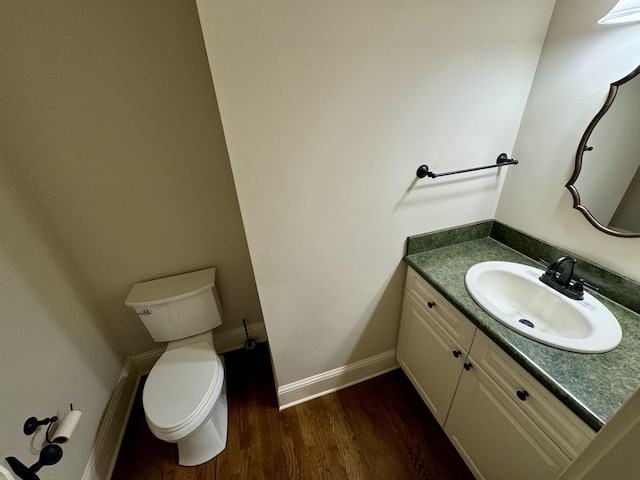 bathroom featuring toilet, vanity, baseboards, and wood finished floors