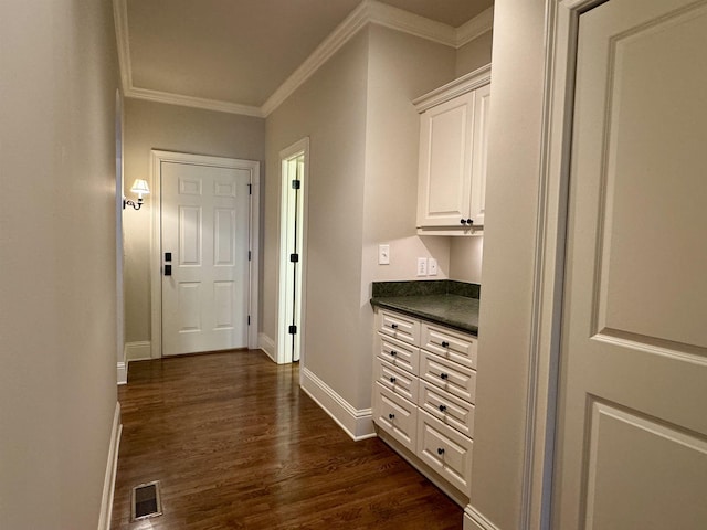 hallway featuring crown molding, dark wood-style floors, visible vents, and baseboards