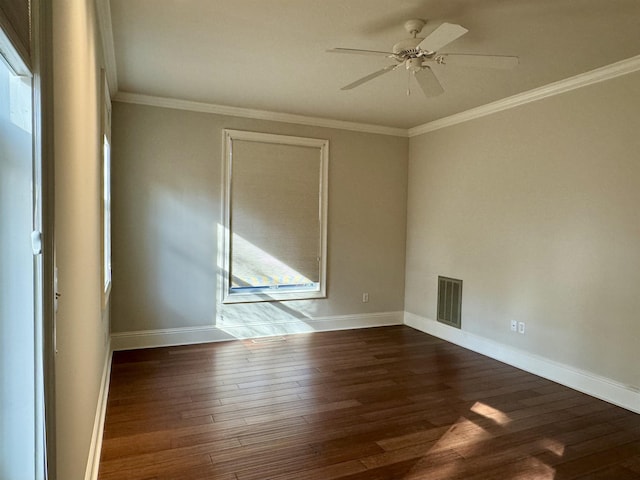 empty room featuring visible vents, crown molding, baseboards, and wood finished floors