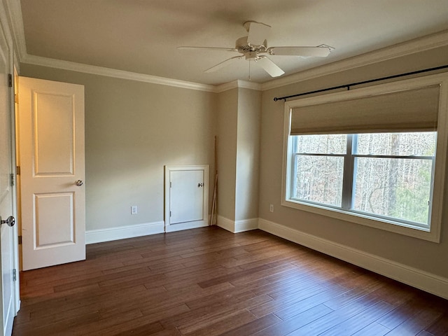 unfurnished room featuring dark wood-type flooring, a ceiling fan, baseboards, and ornamental molding