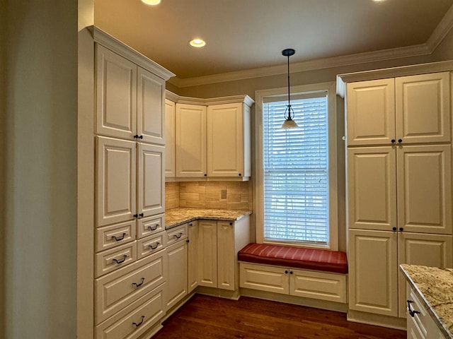 kitchen with light stone counters, white cabinetry, crown molding, dark wood-style flooring, and hanging light fixtures