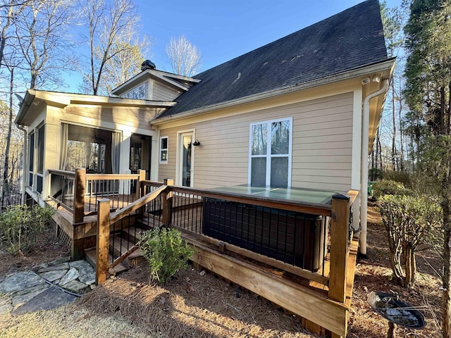 rear view of property featuring a deck and roof with shingles