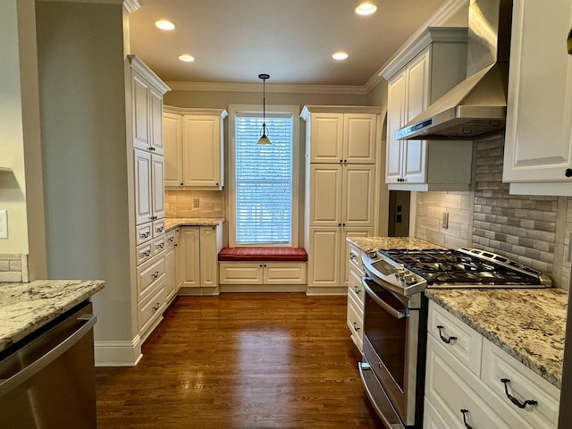 kitchen featuring light stone countertops, dark wood finished floors, appliances with stainless steel finishes, hanging light fixtures, and wall chimney exhaust hood