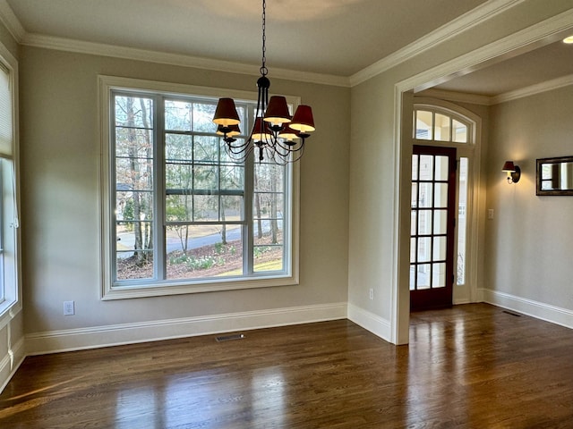 unfurnished dining area with visible vents, dark wood-type flooring, baseboards, a chandelier, and ornamental molding