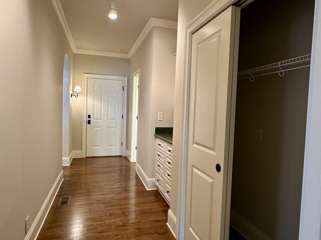 corridor featuring dark wood-style floors, visible vents, crown molding, and baseboards