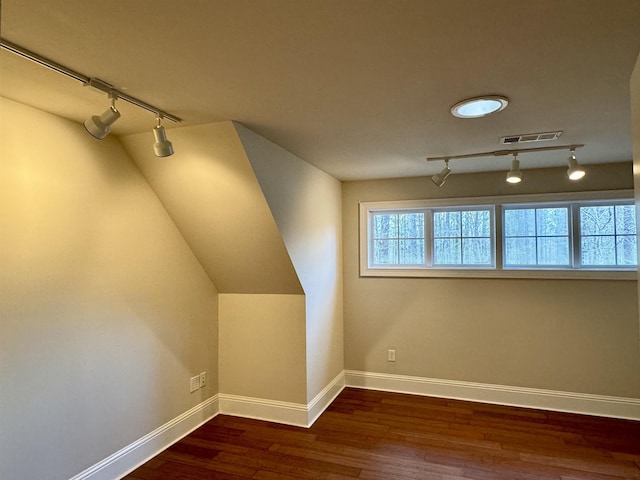 additional living space with visible vents, baseboards, wood finished floors, and vaulted ceiling