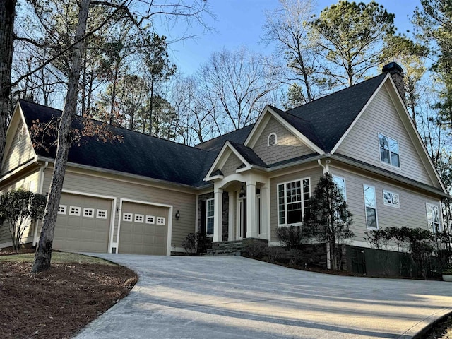 view of front of home with a shingled roof, concrete driveway, a garage, and a chimney