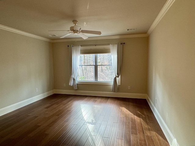 empty room featuring visible vents, baseboards, dark wood-type flooring, and ornamental molding