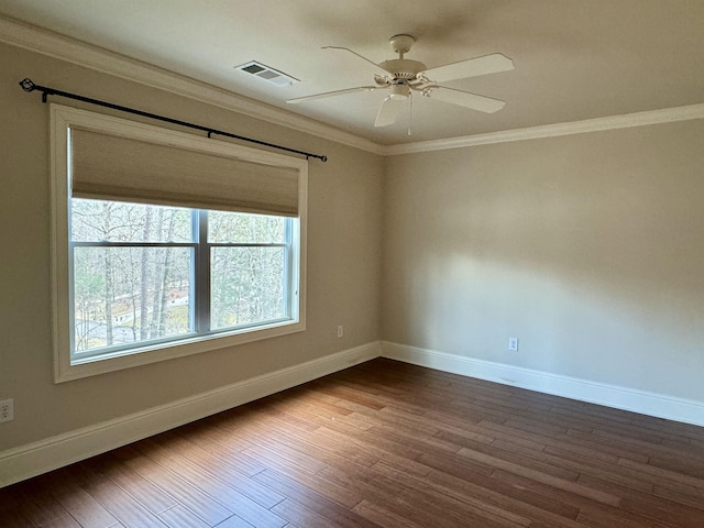 spare room with dark wood finished floors, visible vents, baseboards, and ornamental molding