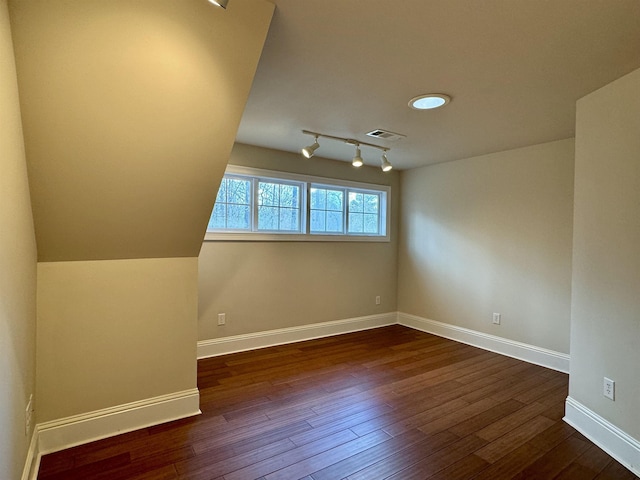 spare room featuring visible vents, baseboards, dark wood-style floors, and rail lighting