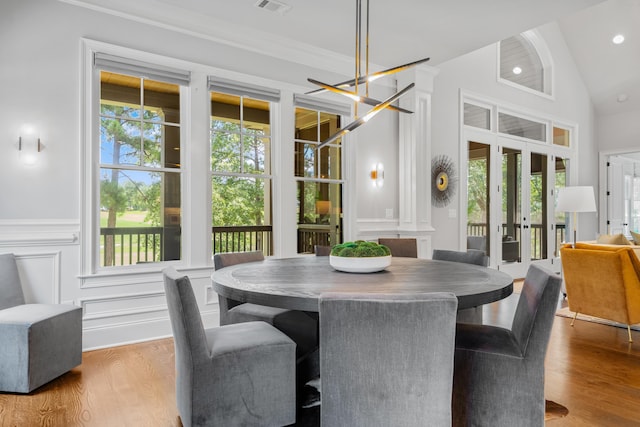 dining space featuring french doors, wood-type flooring, crown molding, and vaulted ceiling