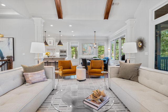 living room featuring beam ceiling, a wealth of natural light, ornamental molding, and ornate columns