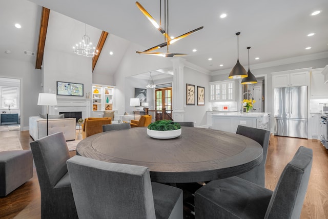 dining room featuring an inviting chandelier, ornamental molding, light hardwood / wood-style flooring, and ornate columns