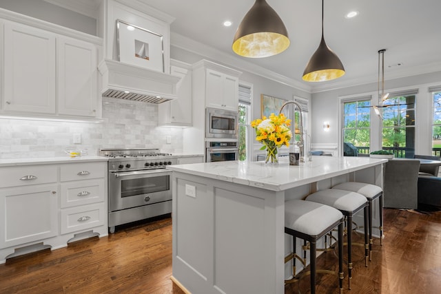 kitchen with stainless steel appliances, white cabinetry, hanging light fixtures, and a kitchen island with sink