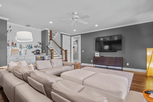 living room featuring dark hardwood / wood-style flooring, ceiling fan, crown molding, and indoor wet bar