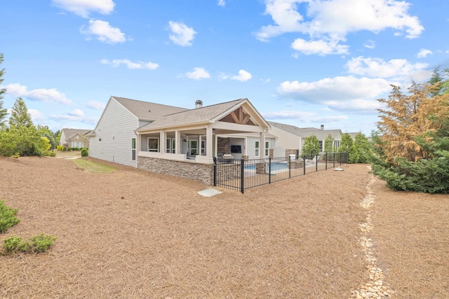 back of house featuring a patio area, fence, stone siding, and roof with shingles