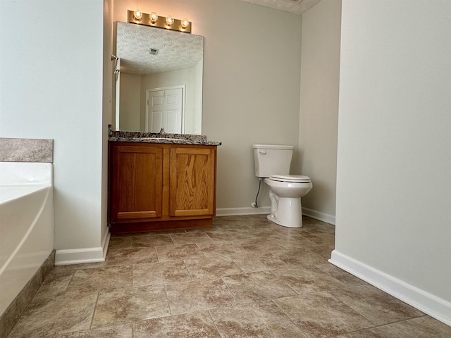 bathroom with a tub to relax in, vanity, toilet, and a textured ceiling