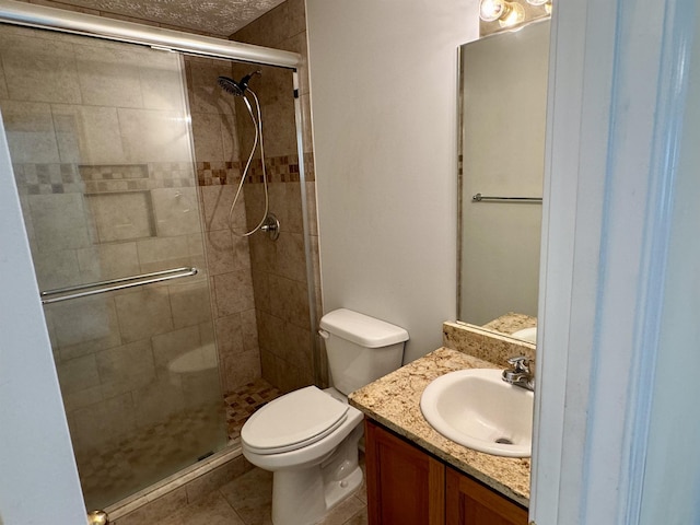 bathroom featuring a shower with door, vanity, tile patterned floors, and toilet