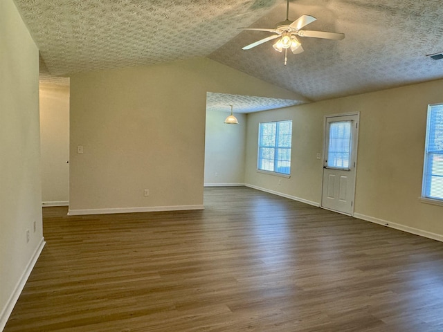 unfurnished living room with ceiling fan, lofted ceiling, dark hardwood / wood-style floors, and a textured ceiling