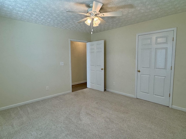 unfurnished bedroom with ceiling fan, light colored carpet, and a textured ceiling