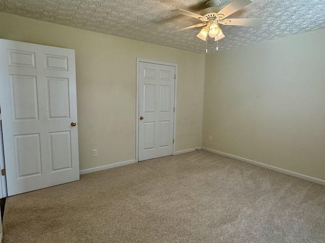 unfurnished bedroom featuring light carpet, ceiling fan, and a textured ceiling