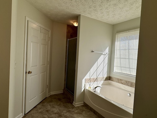 bathroom with independent shower and bath and a textured ceiling