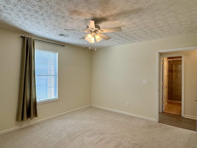 carpeted spare room featuring ceiling fan and a textured ceiling